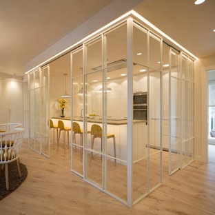 Ejemplo de cocina comedor de galera, contemporánea, de tamaño medio, con fregadero bajoencimera, armarios con paneles lisos, puertas de armario blancas, encimera de cuarzo compacto, electrodomésticos de acero inoxidable, suelo laminado, península, suelo marrón y encimeras beige