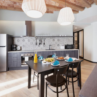 Ejemplo de cocina lineal, urbana, abierta, con fregadero encastrado, armarios con paneles lisos, puertas de armario marrones, salpicadero multicolor, electrodomésticos de acero inoxidable, suelo de madera clara y encimeras blancas