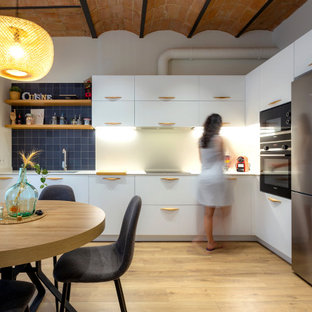 Imagen de cocina en L, costera, de tamaño medio, abierta, sin isla, con fregadero de un seno, puertas de armario blancas, electrodomésticos de acero inoxidable, suelo de madera en tonos medios y suelo marrón