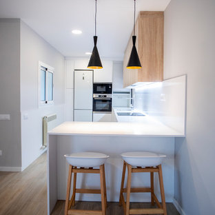 Diseño de cocina en U, moderna, de tamaño medio, abierta, sin isla, con fregadero de un seno, puertas de armario de madera oscura, salpicadero blanco, electrodomésticos blancos, suelo de madera en tonos medios, suelo marrón, encimeras blancas y armarios con paneles lisos