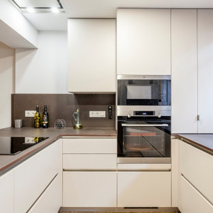 Modelo de cocina en U, contemporánea, con fregadero bajoencimera, armarios con paneles lisos, puertas de armario blancas, salpicadero marrón, península y encimeras marrones