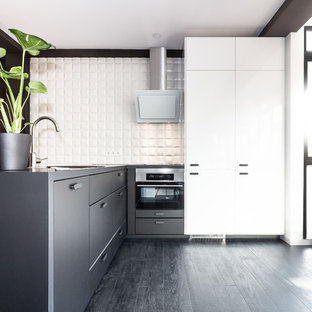 Foto de cocina en L, contemporánea, de tamaño medio, con armarios con paneles lisos, puertas de armario negras, salpicadero blanco, electrodomésticos de acero inoxidable, península y suelo negro
