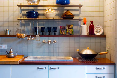 Imagen de cocina lineal ecléctica pequeña abierta con fregadero encastrado, armarios abiertos, encimera de madera, salpicadero azul, salpicadero de azulejos de cerámica, suelo de cemento y suelo gris