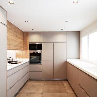 Modelo de cocina en U, moderna, grande, cerrada, sin isla, con fregadero integrado, armarios con paneles lisos, puertas de armario grises, salpicadero blanco, encimeras blancas, electrodomésticos con paneles, suelo de cemento y suelo beige