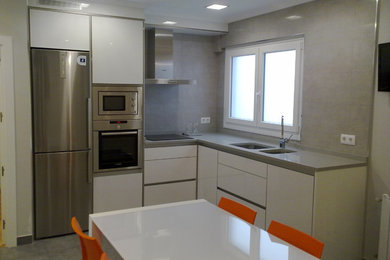 Design ideas for a medium sized traditional l-shaped kitchen/diner in Bilbao with a double-bowl sink, flat-panel cabinets, white cabinets, stainless steel appliances and no island.
