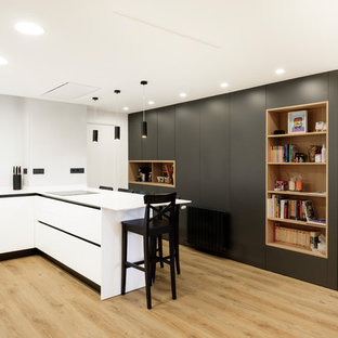 Immagine di una grande cucina ad U contemporanea con ante lisce, ante bianche, top in quarzo composito, paraspruzzi bianco, elettrodomestici da incasso, pavimento in laminato, penisola e top bianco