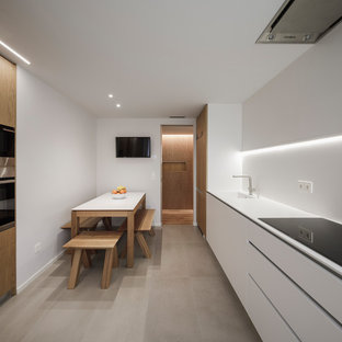 Diseño de cocina comedor lineal, moderna, sin isla, con fregadero integrado, armarios con paneles lisos, puertas de armario blancas, salpicadero blanco, electrodomésticos de acero inoxidable, suelo gris y encimeras blancas