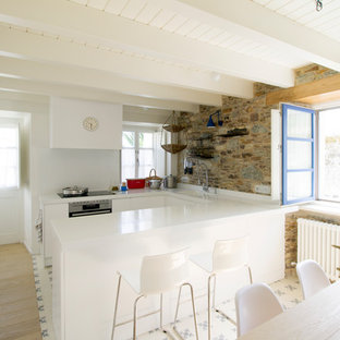 Imagen de cocina comedor en U, mediterránea, con armarios con paneles lisos, puertas de armario blancas, electrodomésticos de acero inoxidable, península, suelo multicolor y encimeras blancas