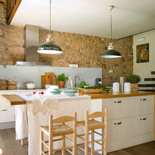 Immagine di una grande cucina parallela country chiusa con ante lisce, ante beige, top in legno, paraspruzzi grigio, paraspruzzi in lastra di pietra, elettrodomestici in acciaio inossidabile, pavimento in legno massello medio e isola
