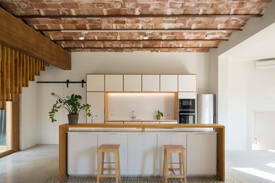 バルセロナにある広い地中海スタイルのおしゃれなキッチン (フラットパネル扉のキャビネット、白いキャビネット、木材カウンター、白いキッチンパネル、シルバーの調理設備、コンクリートの床、グレーの床) の写真