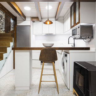 Modelo de cocina en L, urbana, cerrada, con armarios con paneles lisos, puertas de armario blancas, encimera de madera, salpicadero blanco, electrodomésticos de acero inoxidable, suelo de azulejos de cemento, península, suelo beige y encimeras marrones