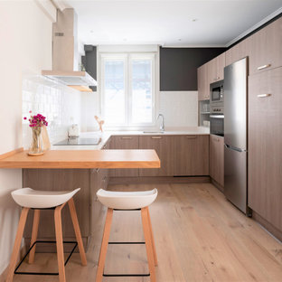 Foto de cocina en U, actual, sin isla, con fregadero bajoencimera, armarios con paneles lisos, puertas de armario de madera oscura, salpicadero blanco, electrodomésticos de acero inoxidable, suelo de madera clara, suelo beige y encimeras blancas