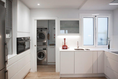 Foto de cocina contemporánea de tamaño medio sin isla con puertas de armario blancas, salpicadero blanco, electrodomésticos de acero inoxidable y encimeras blancas