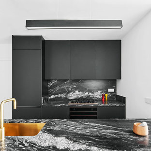 Imagen de cocina de galera, contemporánea, con fregadero bajoencimera, armarios con paneles lisos, puertas de armario negras, salpicadero negro y encimeras negras