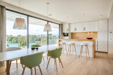 Ejemplo de cocina comedor lineal contemporánea con armarios con paneles lisos, puertas de armario blancas, encimera de madera, salpicadero de madera y una isla