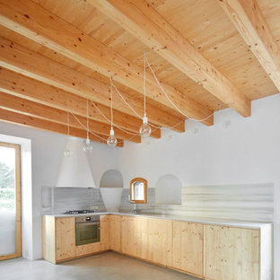 Foto de cocina en L, mediterránea, grande, abierta, sin isla, con armarios con paneles lisos, puertas de armario de madera clara, salpicadero blanco, suelo de cemento y suelo gris