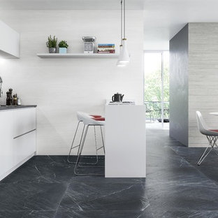 Ejemplo de cocina comedor lineal, contemporánea, con armarios con paneles lisos, puertas de armario blancas, salpicadero verde, península, suelo gris y encimeras grises