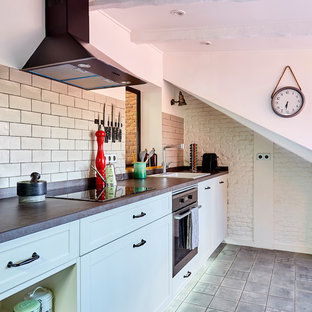 Foto de cocina lineal, mediterránea, sin isla, con armarios estilo shaker, puertas de armario blancas, electrodomésticos de acero inoxidable, encimeras grises, fregadero encastrado, salpicadero beige, salpicadero de azulejos tipo metro, suelo gris y suelo de baldosas de cerámica