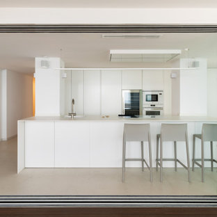 Ejemplo de cocina moderna, grande, con fregadero bajoencimera, armarios con paneles lisos, puertas de armario blancas, electrodomésticos con paneles, suelo de baldosas de porcelana, una isla, suelo beige y encimeras beige