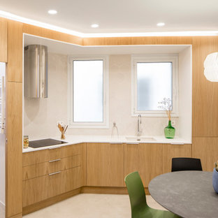 Modelo de cocina comedor lineal, actual, pequeña, sin isla, con fregadero bajoencimera, armarios con paneles lisos, puertas de armario de madera clara, encimera de cuarzo compacto, salpicadero blanco, salpicadero de azulejos de cerámica, electrodomésticos de acero inoxidable, suelo de cemento, suelo gris y encimeras blancas