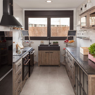 Ejemplo de cocina en U, tradicional renovada, con fregadero de doble seno, armarios con paneles lisos, puertas de armario de madera oscura, salpicadero blanco, electrodomésticos negros, suelo beige y encimeras grises