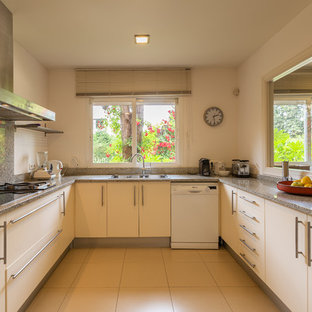 Foto de cocina en U, contemporánea, grande, sin isla, con armarios con paneles lisos, puertas de armario beige, encimera de granito, fregadero encastrado, salpicadero verde, salpicadero de losas de piedra, electrodomésticos blancos y suelo beige