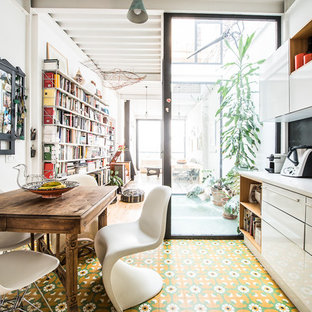 Imagen de cocina comedor lineal, ecléctica, de tamaño medio, sin isla, con armarios con paneles lisos, puertas de armario blancas, salpicadero negro, suelo de baldosas de cerámica, suelo multicolor y electrodomésticos negros