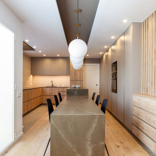 Diseño de cocina en U, actual, grande, con fregadero encastrado, armarios con paneles lisos, puertas de armario de madera oscura, electrodomésticos con paneles, dos o más islas, suelo beige y encimeras grises