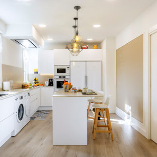 Foto de cocina en L, contemporánea, de tamaño medio, cerrada, con armarios con paneles lisos, puertas de armario blancas, salpicadero beige, electrodomésticos blancos, una isla, suelo de madera clara, suelo beige y encimeras beige