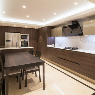 Modelo de cocina comedor contemporánea con armarios con paneles lisos, puertas de armario de madera en tonos medios, electrodomésticos de acero inoxidable, península, encimeras blancas, fregadero bajoencimera, salpicadero blanco y suelo multicolor