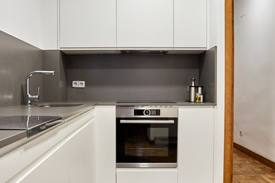 Foto de cocinas en L minimalista de tamaño medio cerrada sin isla con armarios con paneles lisos, puertas de armario blancas y salpicadero verde