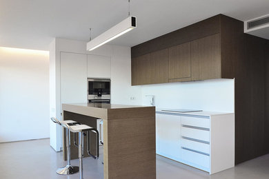 Imagen de cocina lineal contemporánea de tamaño medio abierta con armarios con paneles lisos, puertas de armario blancas, salpicadero blanco, electrodomésticos de acero inoxidable y una isla
