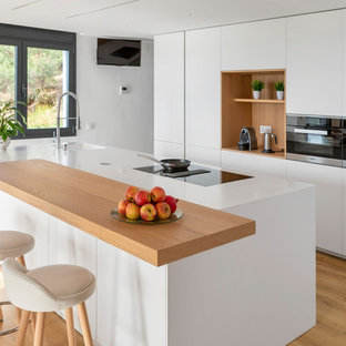 Diseño de cocina costera con armarios con paneles lisos, puertas de armario blancas, una isla, encimeras blancas, fregadero de un seno y suelo de madera clara