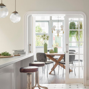 Design ideas for a large shabby-chic style single-wall open plan kitchen in Barcelona with a double-bowl sink, white cabinets, marble benchtops, stainless steel appliances, medium hardwood floors, a peninsula, multi-coloured floor and white benchtop.