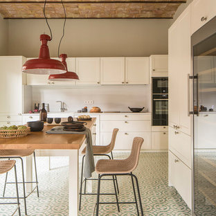 Foto de cocina comedor lineal, mediterránea, de tamaño medio, con fregadero integrado, puertas de armario blancas, encimera de madera, salpicadero blanco, salpicadero de piedra caliza, una isla, encimeras marrones, armarios estilo shaker, electrodomésticos negros y suelo verde