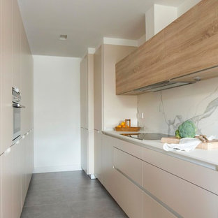 Inspiration for a mid-sized shabby-chic style galley kitchen in Bilbao with flat-panel cabinets, beige cabinets, white splashback, marble splashback and grey floor.