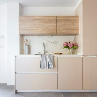 Modelo de cocina lineal, actual, pequeña, con armarios con paneles lisos, puertas de armario beige, salpicadero blanco, salpicadero de mármol, suelo gris y fregadero bajoencimera