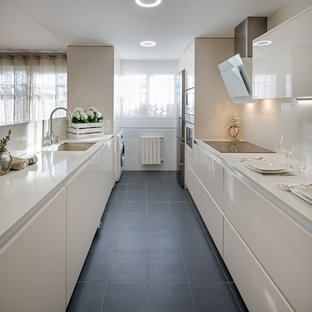 Imagen de cocina de galera, contemporánea, de tamaño medio, cerrada, sin isla, con armarios con paneles lisos, puertas de armario blancas, encimera de cuarzo compacto, salpicadero blanco, electrodomésticos de acero inoxidable, suelo de baldosas de cerámica, suelo negro y fregadero bajoencimera