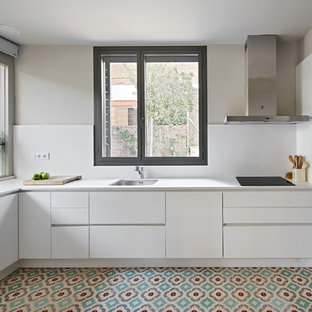 Modelo de cocina en L, actual, con fregadero bajoencimera, armarios con paneles lisos, puertas de armario blancas, electrodomésticos de acero inoxidable, suelo multicolor y encimeras blancas