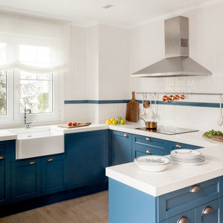 Ejemplo de cocina en U, marinera, de tamaño medio, con puertas de armario azules, salpicadero blanco, salpicadero de azulejos de cerámica, península, fregadero sobremueble, armarios estilo shaker y suelo beige