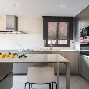 Ejemplo de cocina en L, contemporánea, con fregadero bajoencimera, armarios con paneles lisos, puertas de armario grises, salpicadero blanco, salpicadero de losas de piedra, electrodomésticos de acero inoxidable, una isla, suelo gris y encimeras blancas