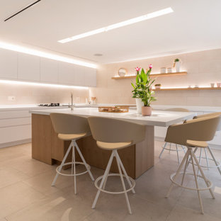 Ejemplo de cocina en L, contemporánea, grande, con fregadero bajoencimera, armarios con paneles lisos, puertas de armario blancas, salpicadero beige, electrodomésticos con paneles, suelo de baldosas de porcelana, una isla, suelo negro y encimeras blancas