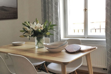 Modelo de comedor escandinavo pequeño abierto con paredes blancas y suelo de madera en tonos medios