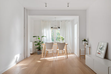 Diseño de comedor minimalista de tamaño medio cerrado con paredes blancas, suelo de madera clara y suelo beige