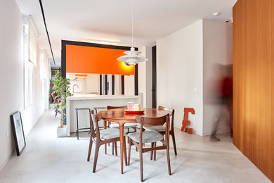 Aménagement d'une grande salle à manger ouverte sur le salon moderne avec un mur blanc, sol en béton ciré, aucune cheminée et un sol gris.