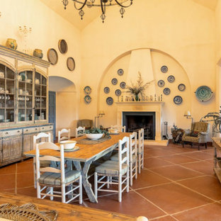 Diseño de comedor mediterráneo con paredes amarillas, chimenea tradicional y suelo marrón