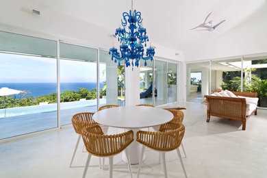 Cette photo montre une salle à manger ouverte sur le salon bord de mer avec un mur blanc et un sol blanc.