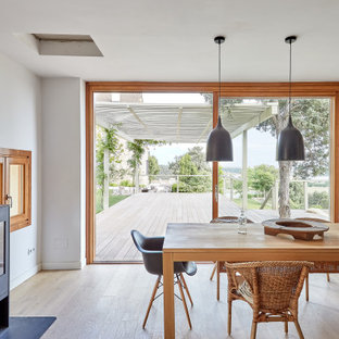 Immagine di una sala da pranzo mediterranea di medie dimensioni con pareti bianche, parquet chiaro, stufa a legna, cornice del camino in metallo e pavimento beige