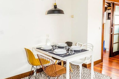 Modelo de comedor escandinavo de tamaño medio abierto con paredes blancas y suelo de madera en tonos medios