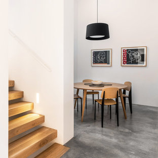 Diseño de comedor actual, sin chimenea, con paredes blancas, suelo de cemento y suelo gris